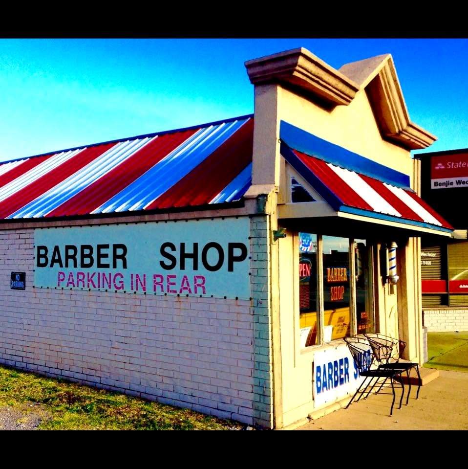 Doc's Barber Shop storefront on S Broadway in Edmond — red, white and blue striped awning and roof, OPEN sign in the window